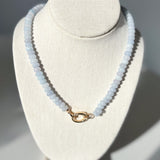 Necklace with light blue beads on a white bust against a gray background