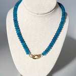 Blue beaded necklace on a white bust against a gray background