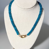 Blue beaded necklace on a white bust against a gray background