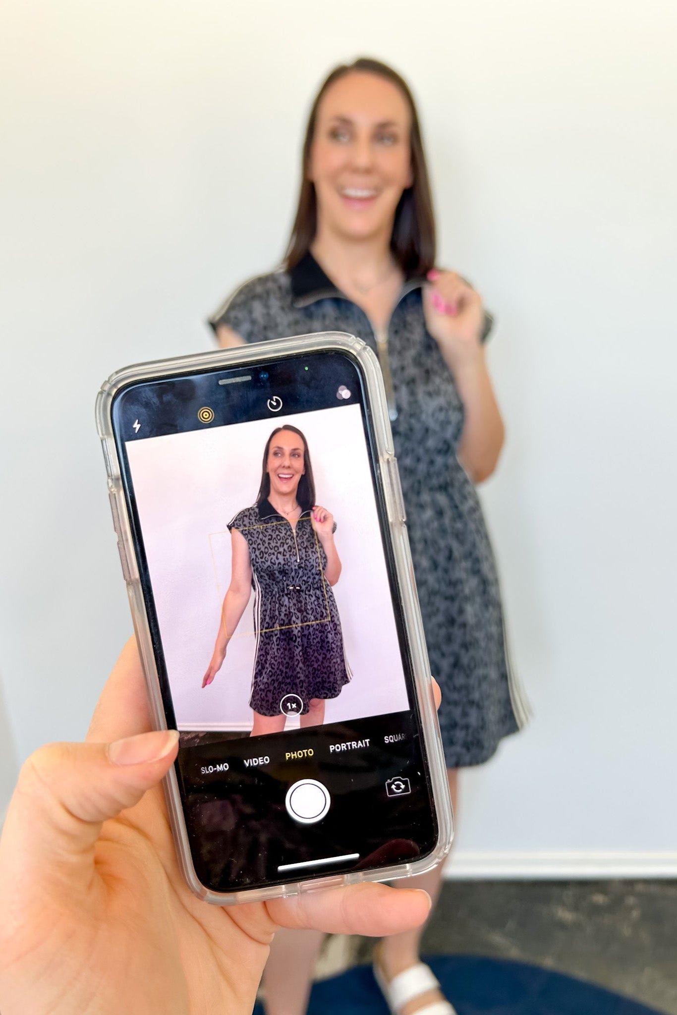 Person taking a photo of another person wearing a dress with a smartphone.