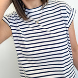 Person wearing a navy and white striped sleeveless top with blue jeans against a plain background