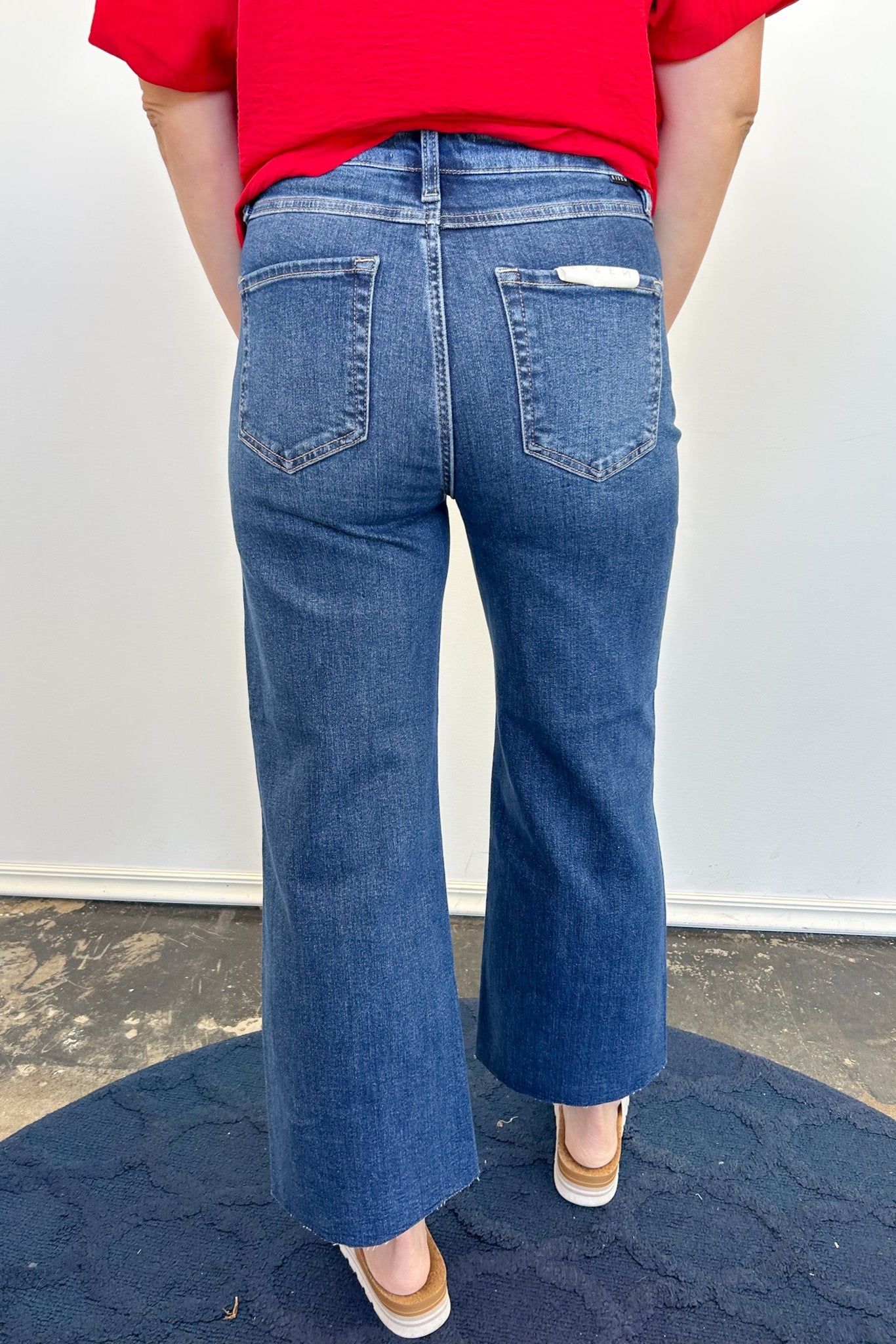 Person wearing blue jeans and a red top on a plain background