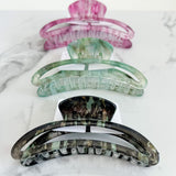 Set of three colorful hair clips on a marble surface