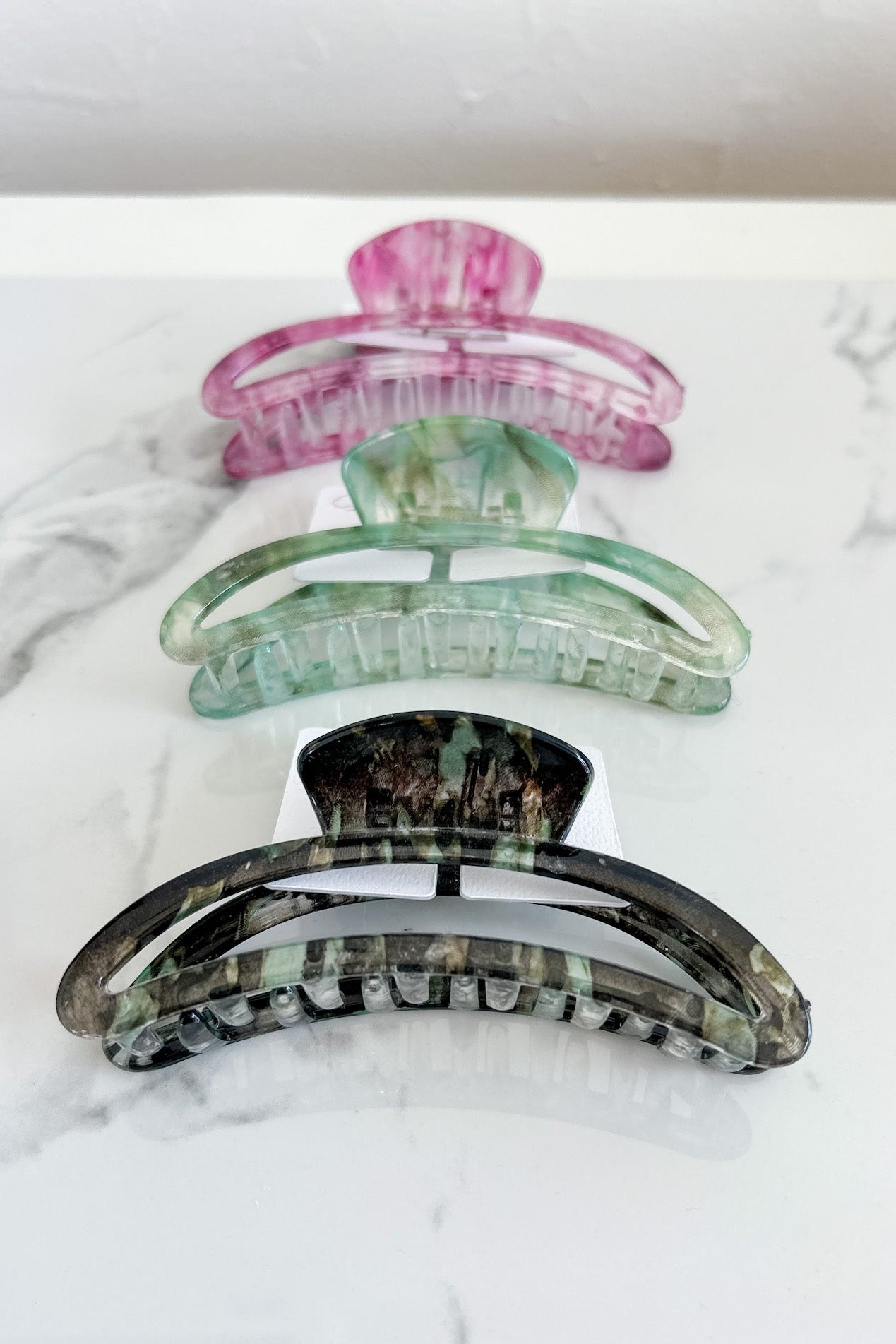 Set of three colorful hair clips on a marble surface