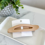 Hair clip on a white dish with a plant in the background