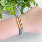 Bracelet on a wrist with a plant in the background