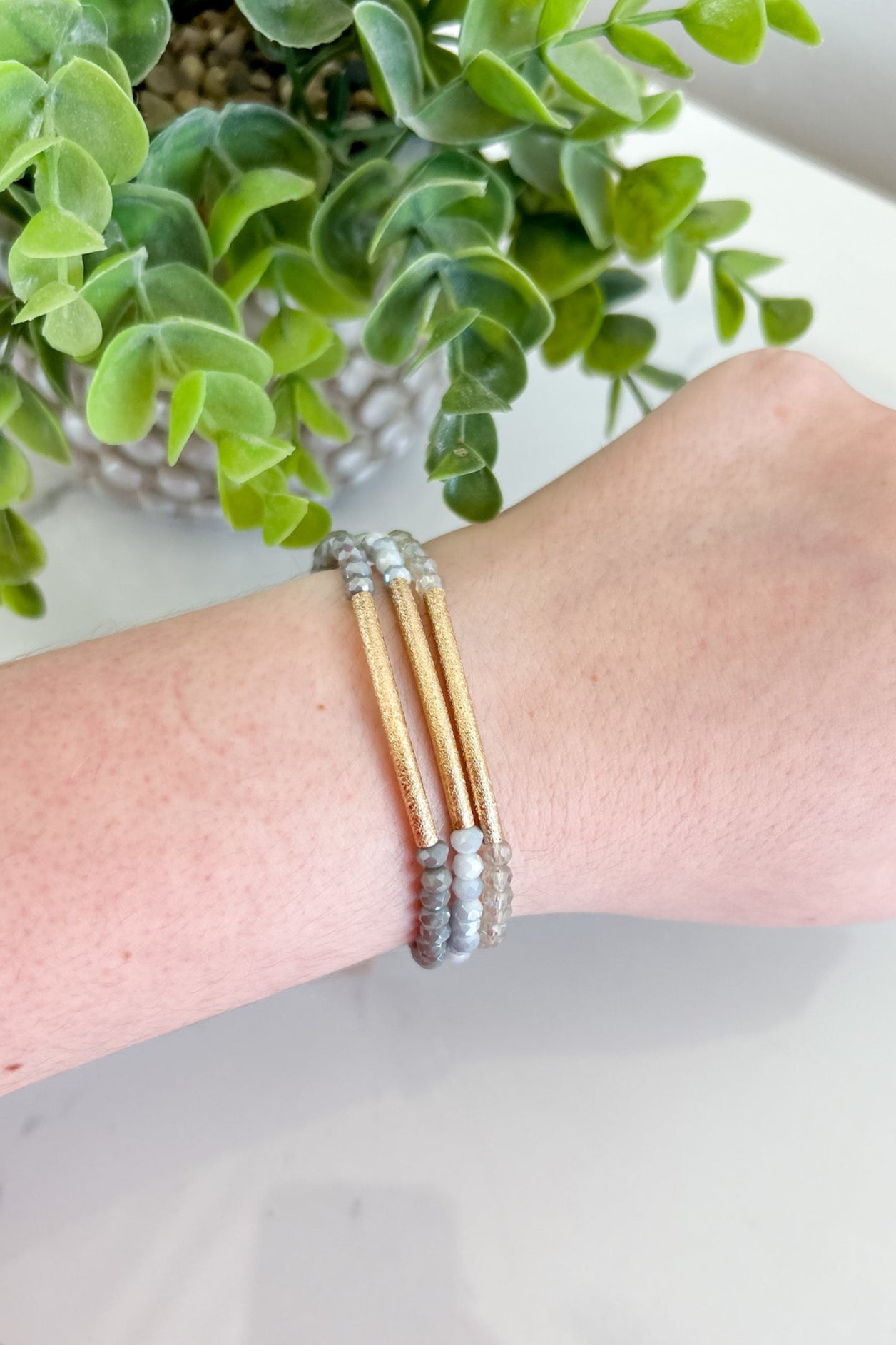 Bracelet on a wrist with a plant in the background
