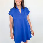 Woman wearing a blue dress against a white wall