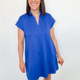 Woman wearing a blue dress against a white wall