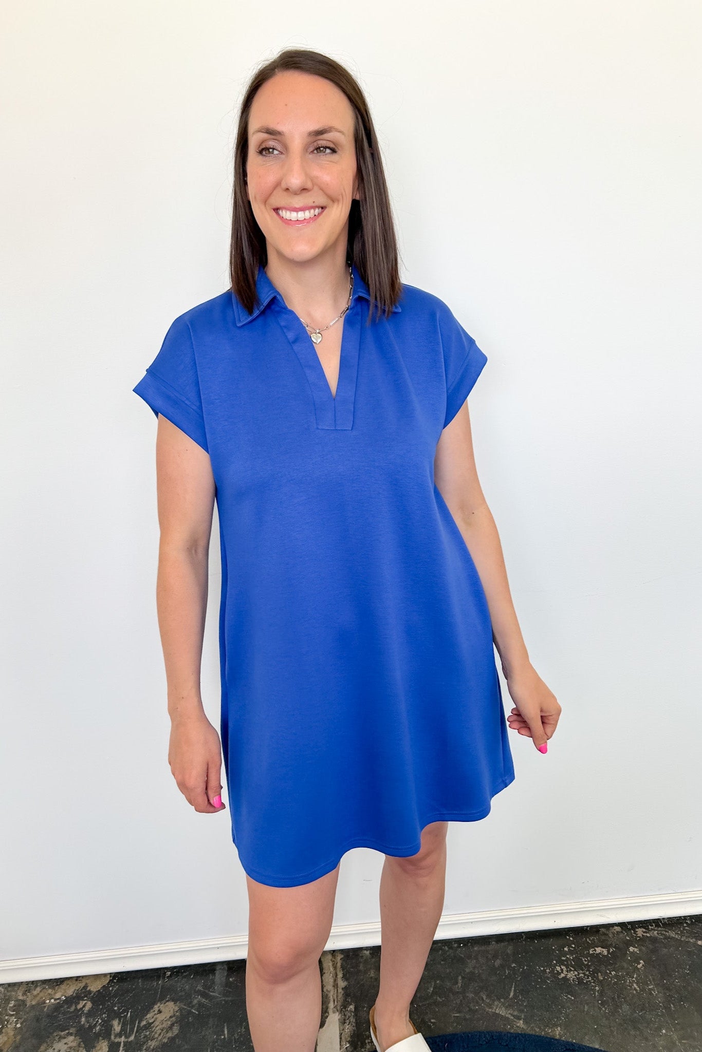 Woman wearing a blue dress against a white wall