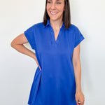 Woman wearing a blue dress against a white wall