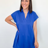 Woman wearing a blue dress against a white wall