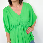 photo of model wearing a bright green, kimono sleeve top with v-neck