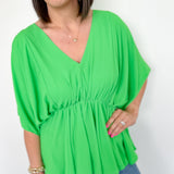 photo of model wearing a bright green, kimono sleeve top with v-neck