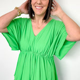 photo of model wearing a bright green, kimono sleeve top with v-neck