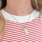 Person wearing a red and white striped shirt with a necklace