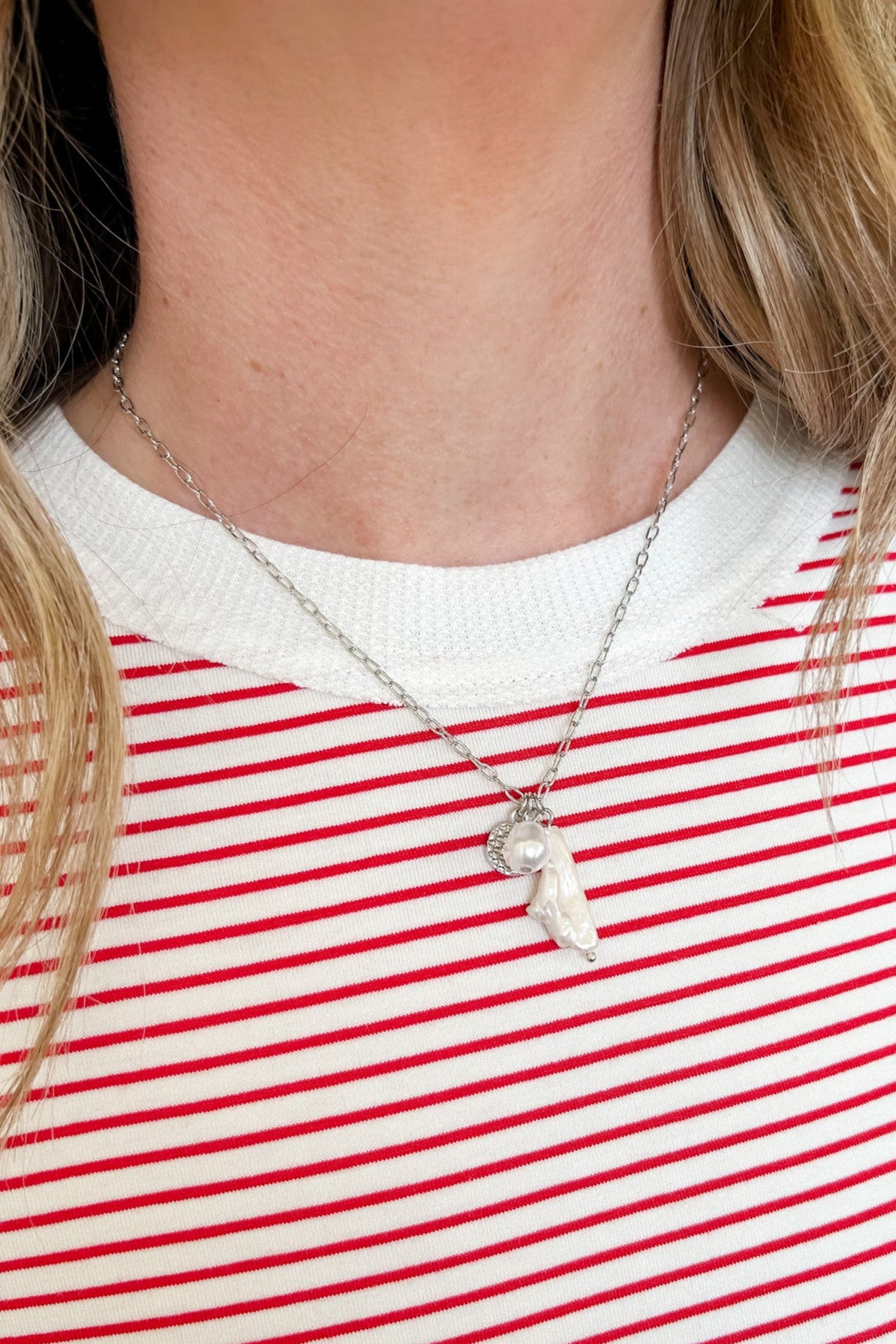 Person wearing a red and white striped shirt with a necklace