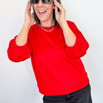 Person wearing a red sweatshirt and black shorts with sunglasses on a white background
