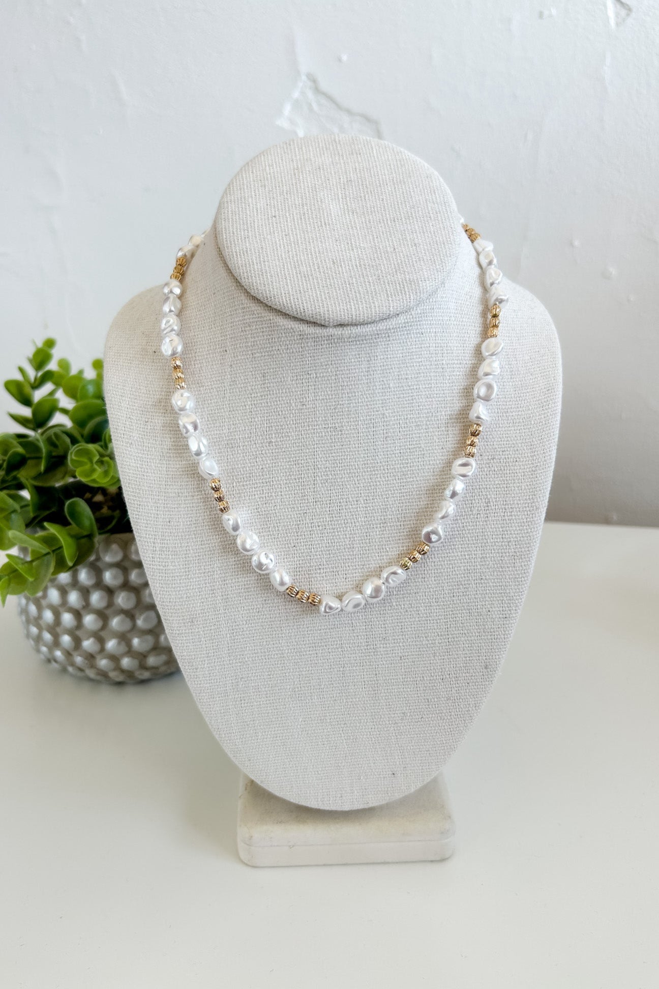 Pearl necklace on a gray bust with a white background