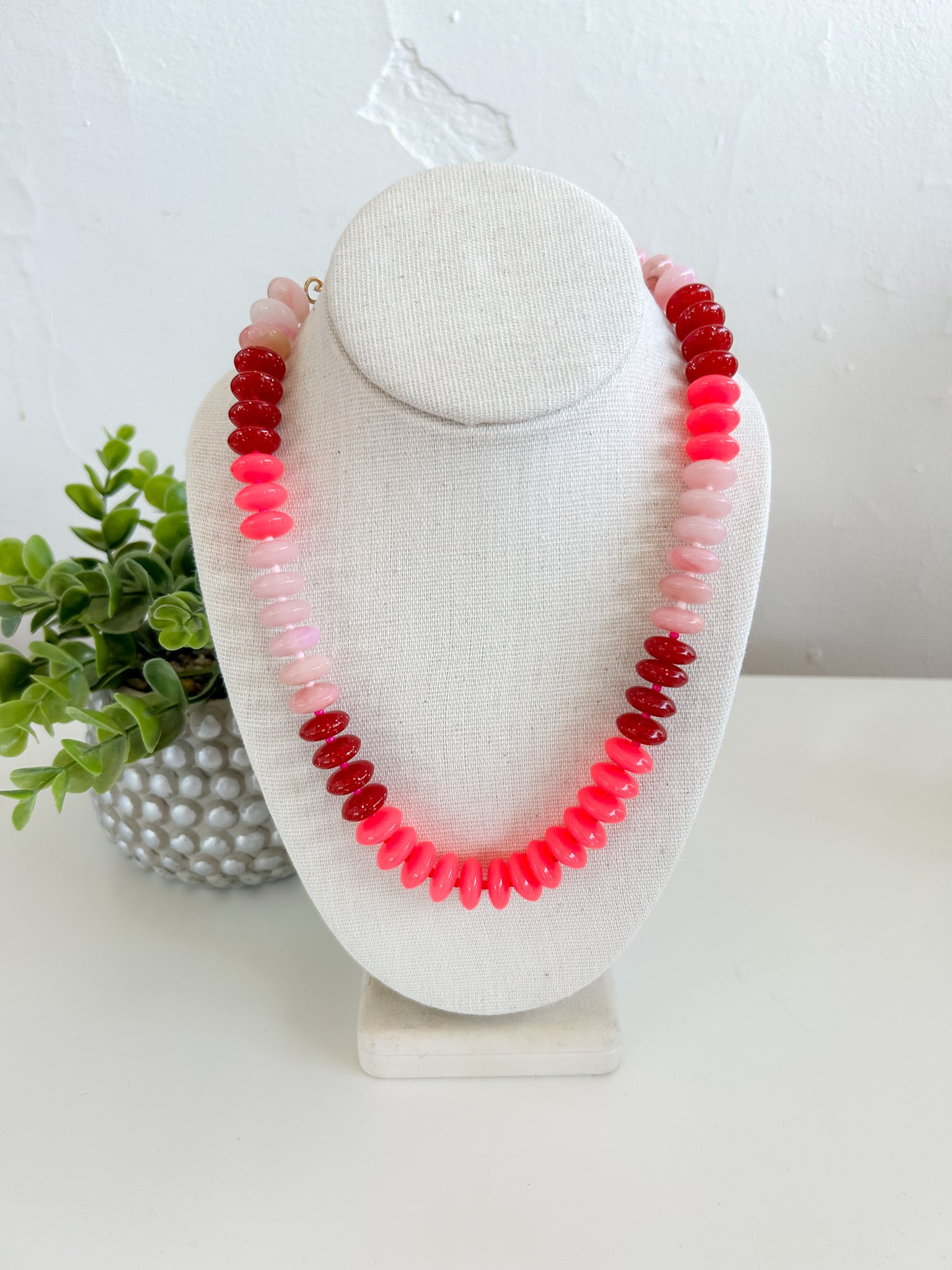 Necklace with multicolored beads on a white bust against a white background