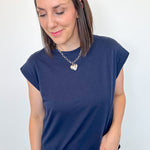 Woman wearing a navy blue t-shirt and jeans against a white background
