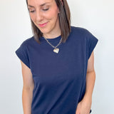 Woman wearing a navy blue t-shirt and jeans against a white background