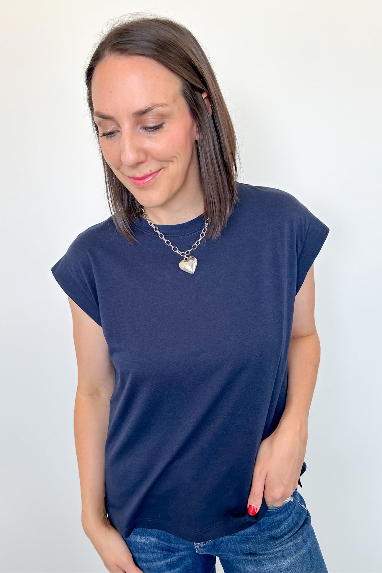 Woman wearing a navy blue t-shirt and jeans against a white background