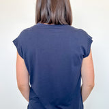 Person wearing a navy blue sleeveless top and jeans against a white background