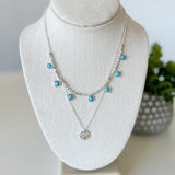 Necklace with turquoise beads on a white bust against a white background