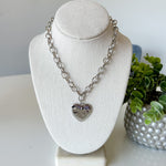 Necklace with a heart pendant on a mannequin bust with a plant in the background