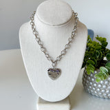 Necklace with a heart pendant on a mannequin bust with a plant in the background