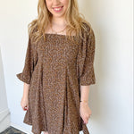 Photo of model wearing a brown, 3/4 puff sleeve dress with pleated skirt 