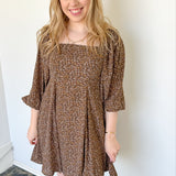 Photo of model wearing a brown, 3/4 puff sleeve dress with pleated skirt 