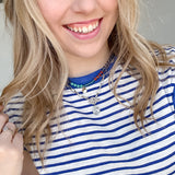 Woman wearing blue and white striped top with necklaces.