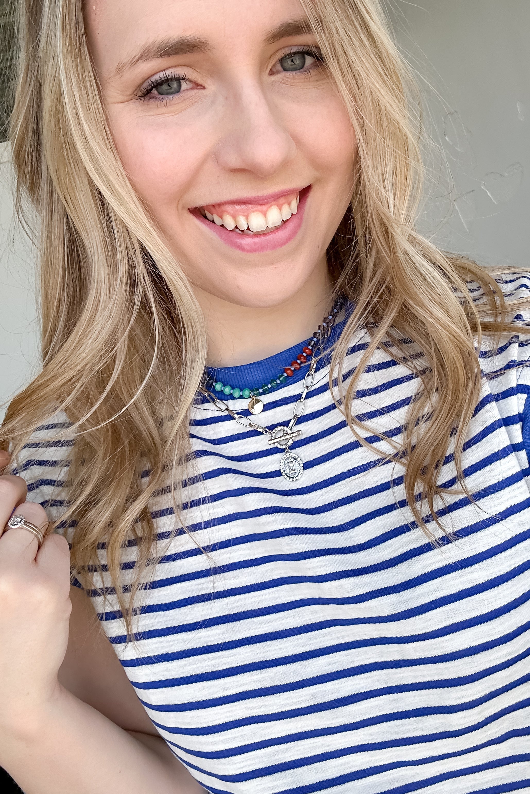 Woman wearing blue and white striped top with necklaces.