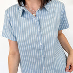 Light blue collared button up top with white stripe details. Short sleeve. 