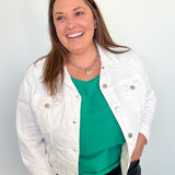 Woman wearing a white jacket over a green top with a plain background