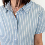 Light blue collared button up top with white stripe details. Short sleeve. 