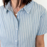 Light blue collared button up top with white stripe details. Short sleeve. 