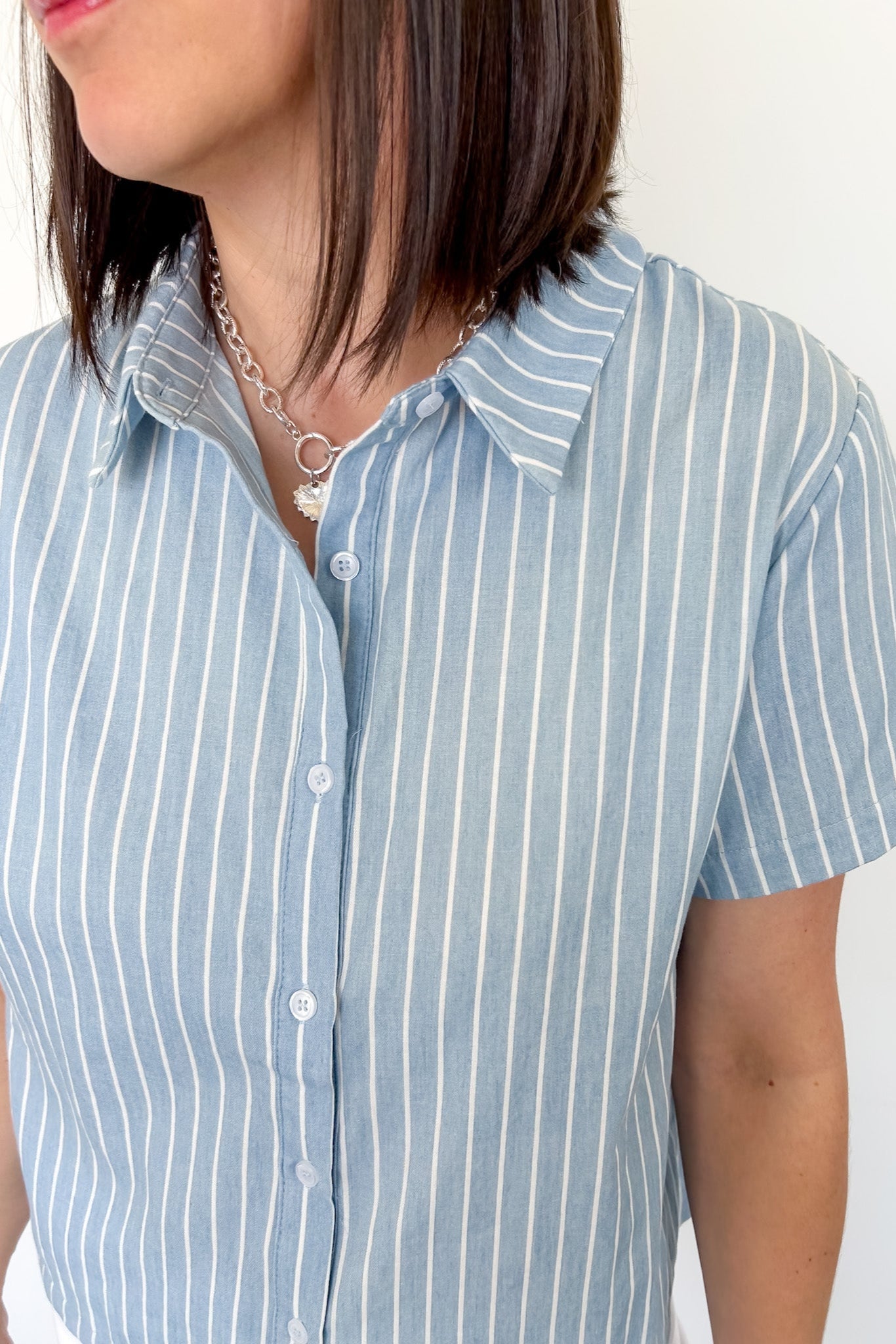 Light blue collared button up top with white stripe details. Short sleeve. 
