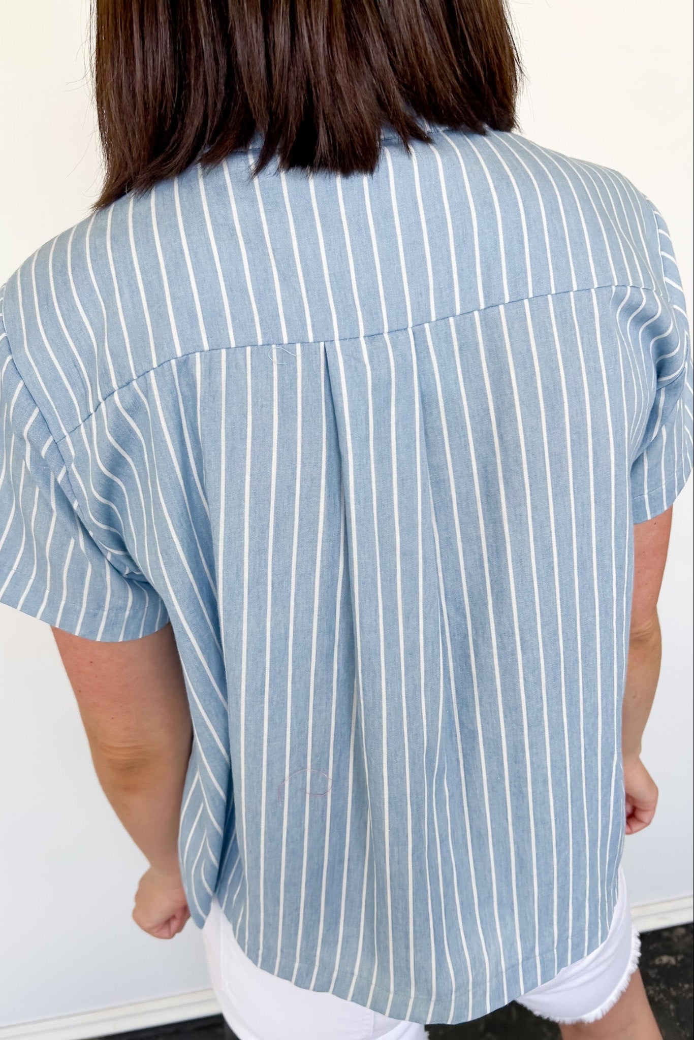 Light blue collared button up top with white stripe details. Short sleeve. 