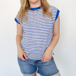 Women wearing blue and white striped top against a white wall.