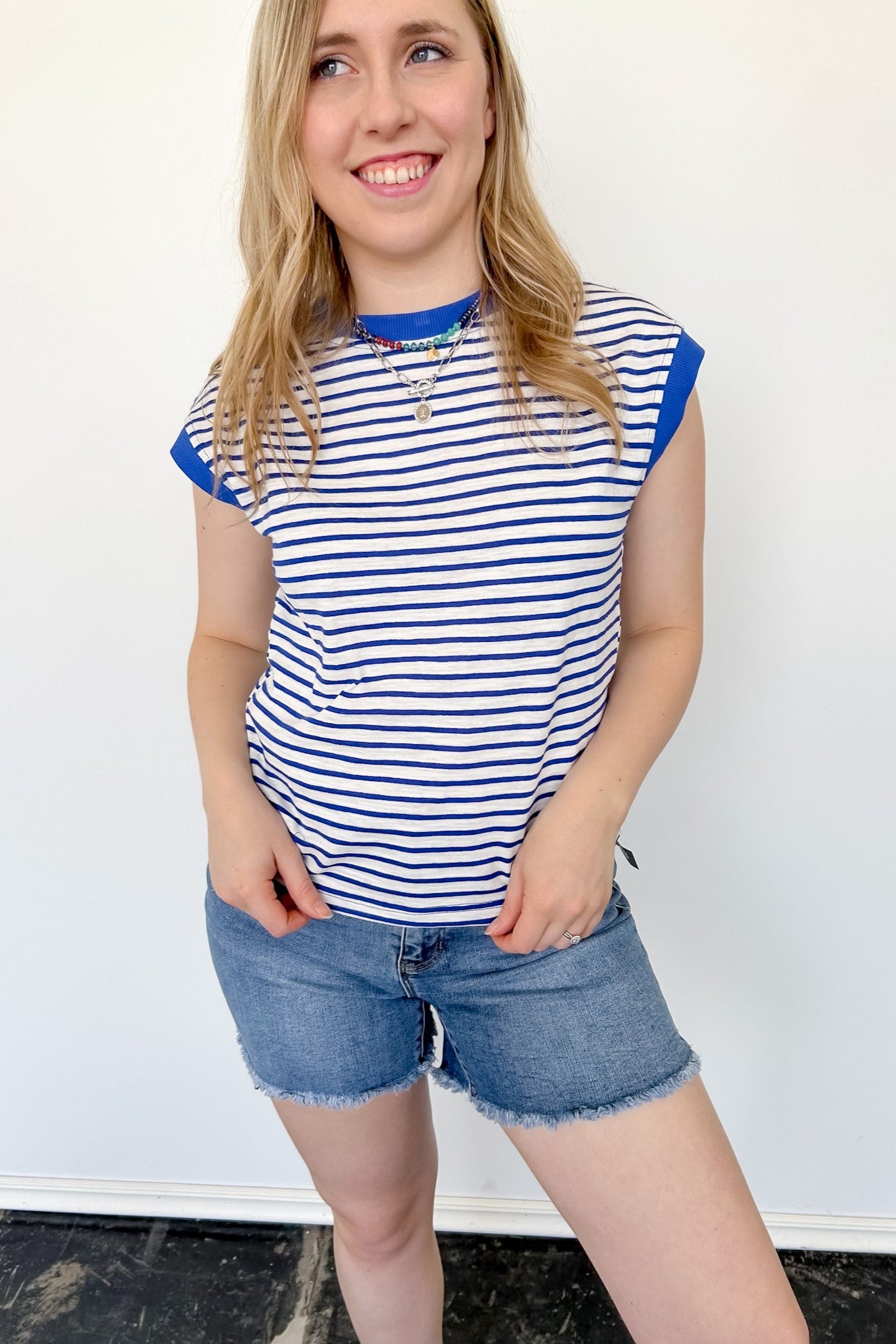 Women wearing blue and white striped top against a white wall.