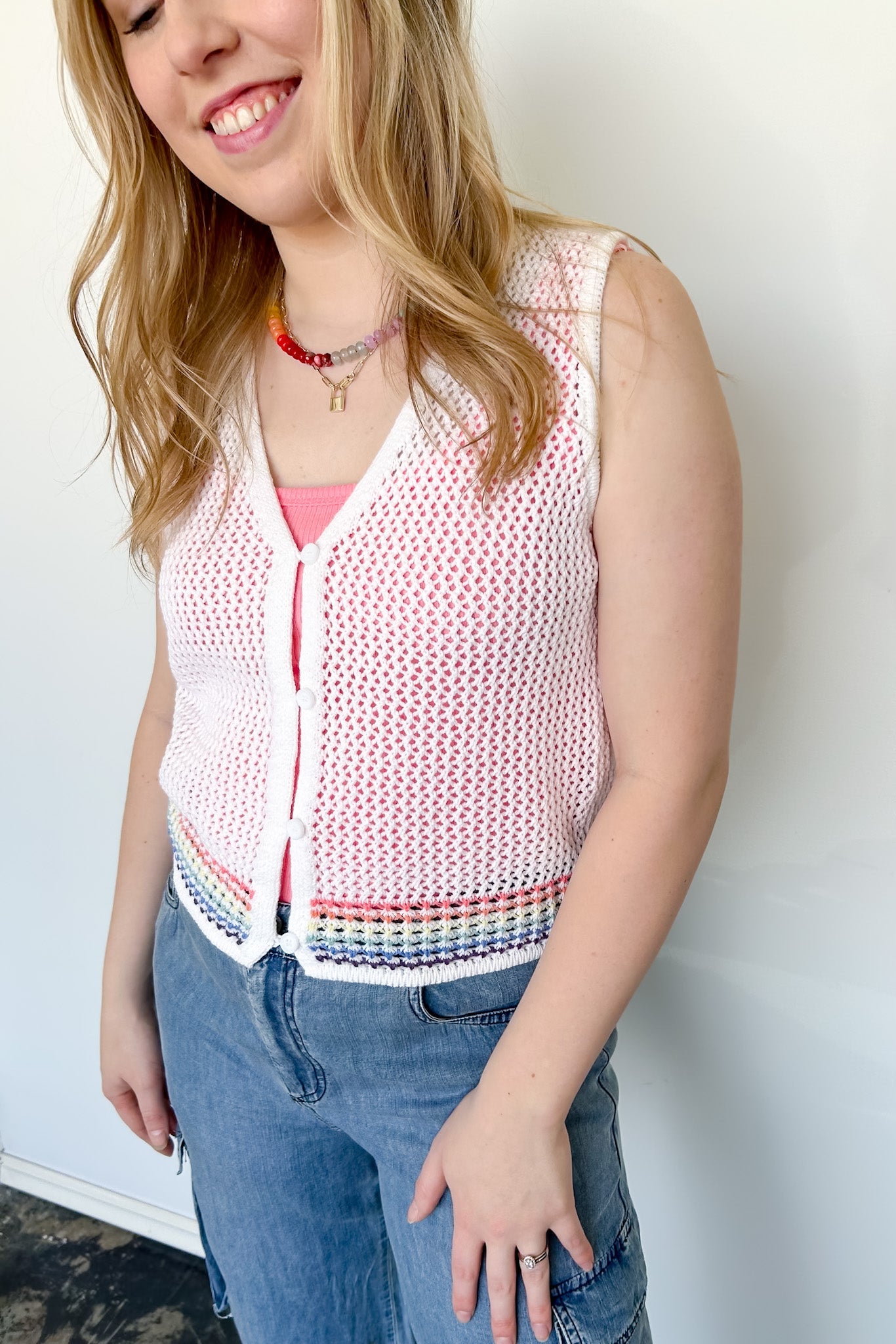 White sweater tank top with rainbow colors around the bottom. Button up. Layered with tank top underneath.