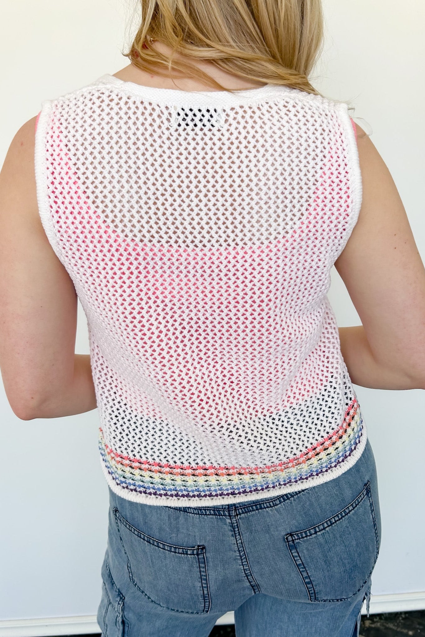 White sweater tank top with rainbow colors around the bottom. Button up. Layered with tank top underneath.