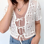 White crochet cropped sweater with three ties in the front. Perfect for layering over a tank or dress.