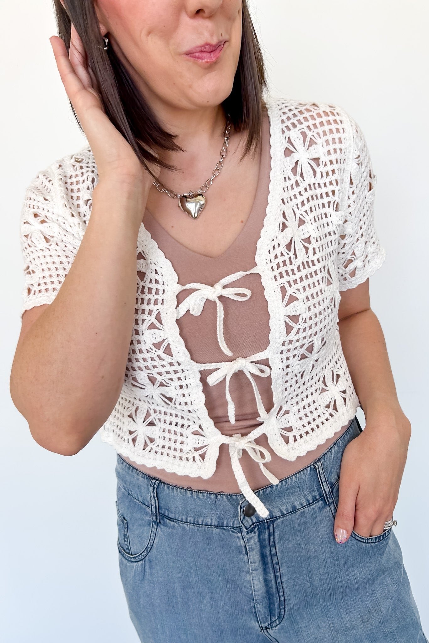 White crochet cropped sweater with three ties in the front. Perfect for layering over a tank or dress.