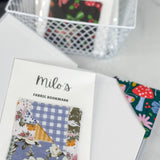 Fabric bookmarks with colorful designs on a white surface, featuring 'milo's' branding.