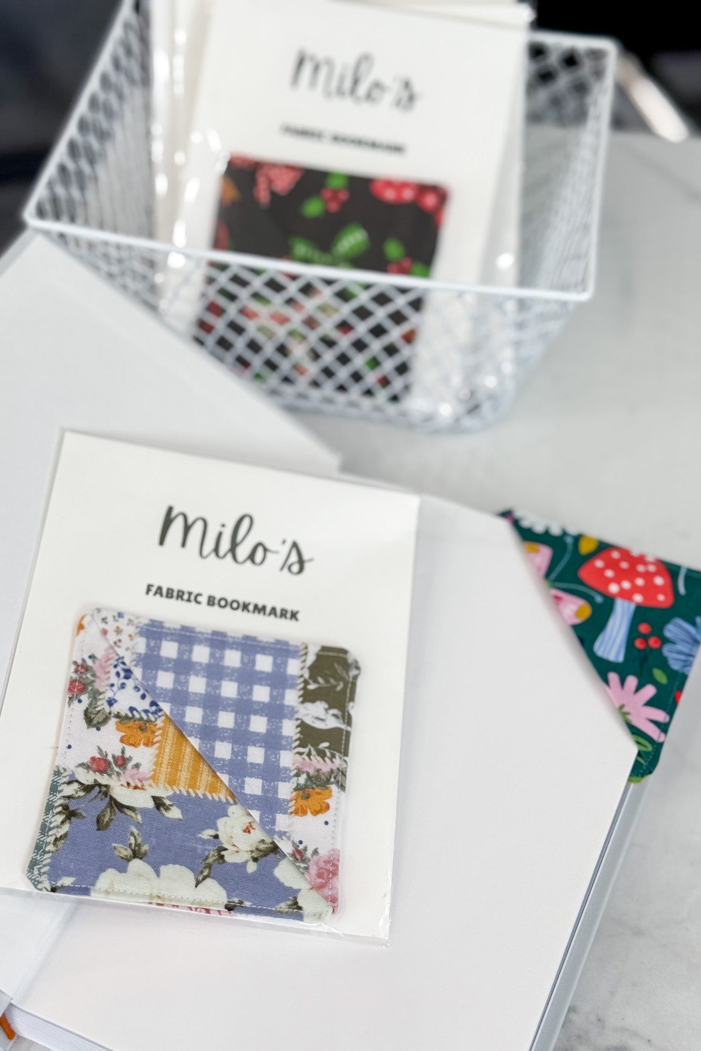 Fabric bookmarks with colorful designs on a white surface, featuring 'milo's' branding.