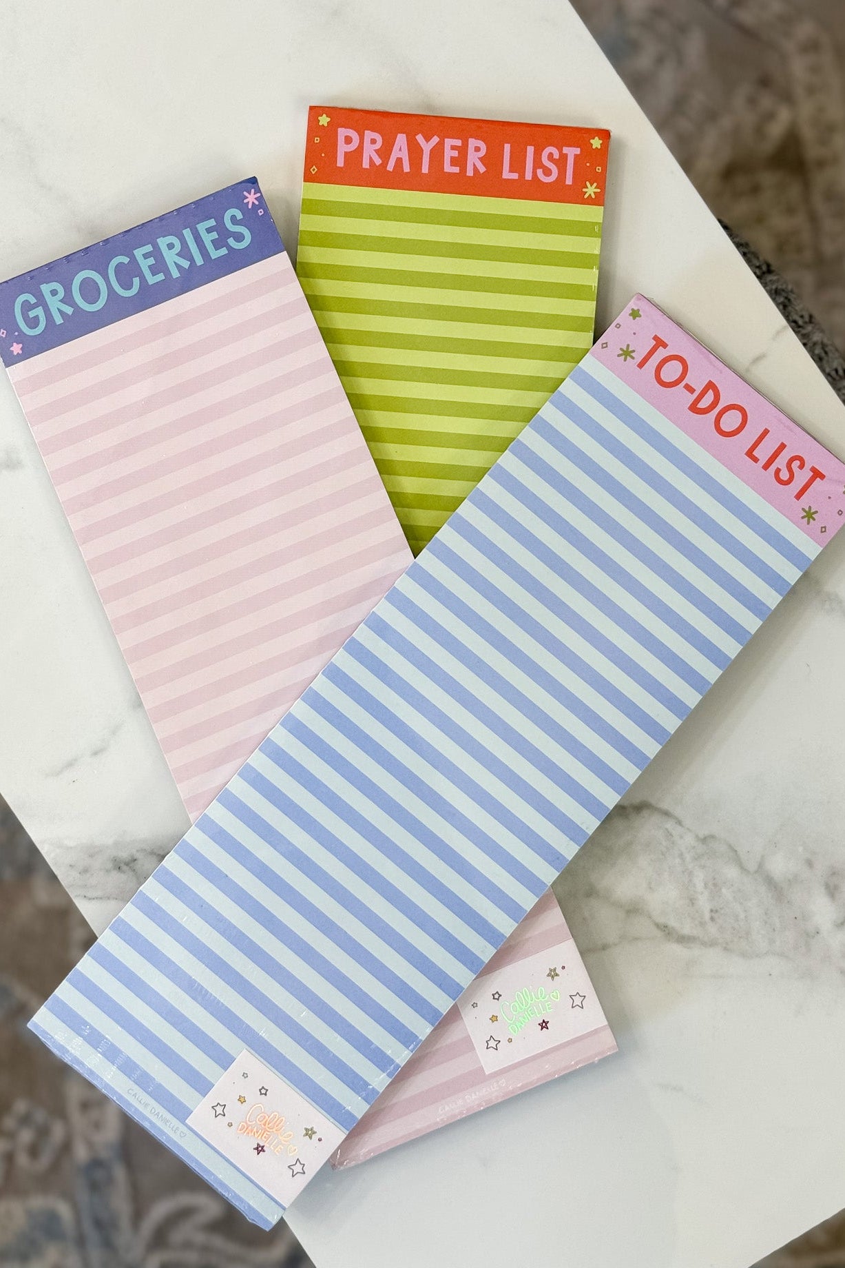 Four small notepads with different designs and text on a marble surface.